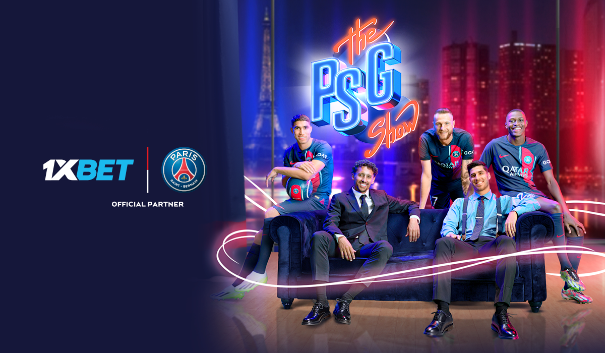 Five men, including three in Paris Saint-Germain kits and two in suits, sit and stand in a neon-lit studio with "The PSG Show" logo and 1XBET official partner branding highlighting an exclusive welecom bonus.